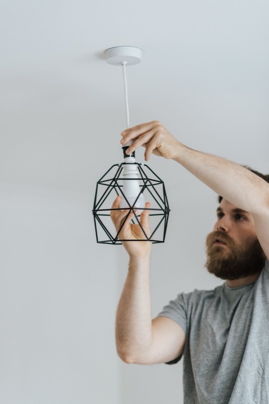 Hands fixing a pendant to a ceiling rose