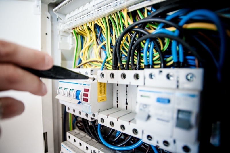 A hand working among the breakers of a distribution board